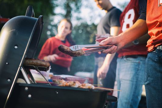 people around a grill at a tailgate